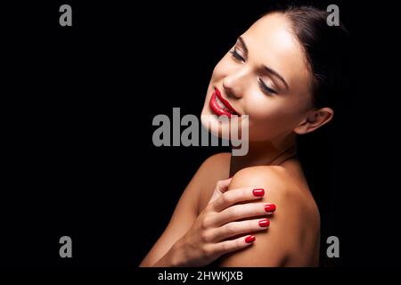 Zerreißendes Rot. Eine junge Frau mit roten Lippen und Nägeln. Stockfoto