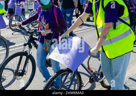 Frau mit einem Fahrrad und einem Papierbanner bei einer Demonstration. Übersetzung: Recht auf legale und sichere Abtreibung. Stockfoto