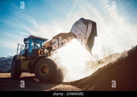 Bulldozer, der zur Kompostierung die Biomasse auf den Stapel legt Stockfoto