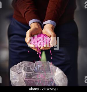 Sieht in Pink perfekt aus. Nahaufnahme eines Mannes, der rosa Plastikgranulat in der Hand hält. Stockfoto