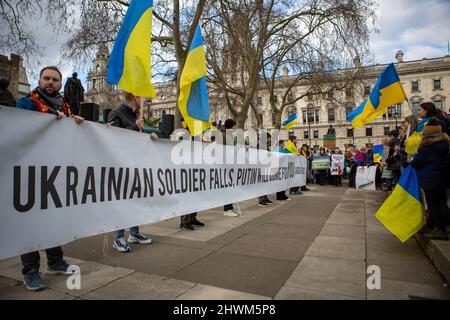 London, Großbritannien. 06. März 2022. Während der Demonstration halten Demonstranten ein Banner und ukrainische Fahnen in der Hand.Hunderte Demonstranten versammelten sich auf dem Parliament Square im Zentrum von London, um gegen den Angriff Russlands auf die Ukraine zu protestieren. Kredit: SOPA Images Limited/Alamy Live Nachrichten Stockfoto