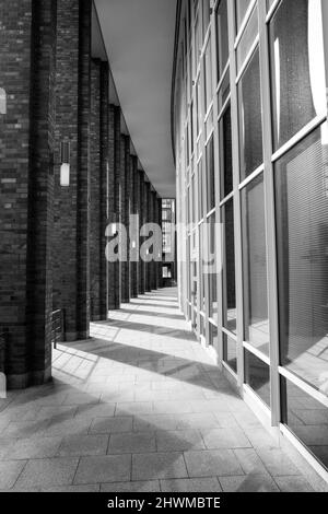 Urbane moderne Straßenfotografie der Hamburger Architektur auf einem geschwungenen Weg zwischen Säulen und Glasfenstern und Schatten auf dem Boden Stockfoto