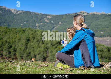 Ein entzückendes Kind, das mit seiner Mutter in freier Wildbahn einen Karton Milch durch einen Strohhalm trinkt Stockfoto