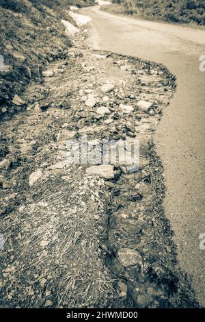 Altes Schwarz-Weiß-Bild von Schnee auf der Straße auf dem Hydnefossen Wasserfall und dem Veslehødn Veslehorn Berg in Hemsedal Norwegen. Stockfoto