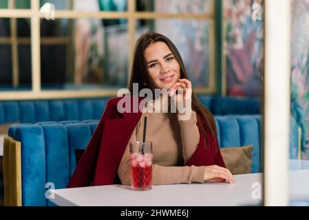 Glückliche Frau in einem Café im Freien, die trinkt und lächelt Stockfoto