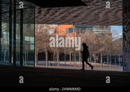 Silhouette eines Mannes, der am Plaça Leonardo da Vinci (Leonardo da Vinci) in der Nähe des Edificio Fórum-Gebäudes in Barcelona, Spanien, entlang läuft. Stockfoto