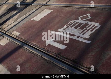 Straßenbahnstrecke auf der Straße in Barcelona, Spanien. Straßenbahn und Pfeile auf der Straße gezogen. Straßenschild. Nahaufnahme der Betonstraße. Öffentliche Verkehrsmittel. Stockfoto