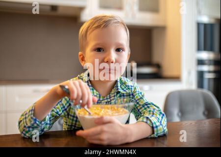 Ruhiges Kind, das Frühstücksflocken isst und nach vorne blickt Stockfoto