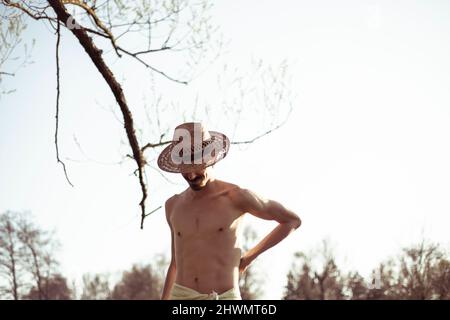 Gesunder, muskulöser, mager junger Mann mit Hut in der Natur Stockfoto