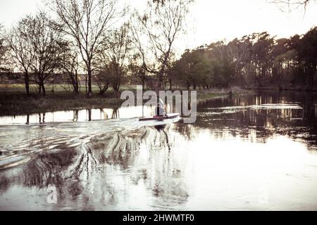 Mann, der auf einem ruhigen Fluss in einer weichen natürlichen Umgebung Kajak gefahren ist Stockfoto