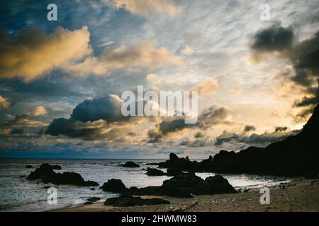 Goldene Wolken am Himmel mit gelbem und blauem Licht über dem Ozean Stockfoto
