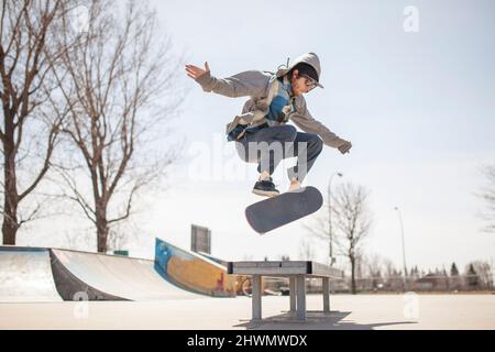 Junger Skateboard-Enthusiast, der einen Kickflip macht Stockfoto