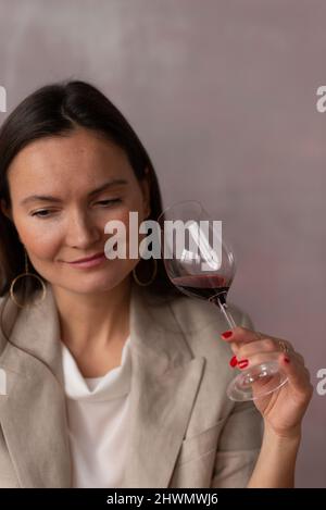 Lächelnde Frau mit einem Glas Wein auf rosa Studiohintergrund Stockfoto