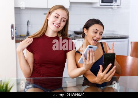 Zwei junge Freundinnen, die am Telefon Selfie machen und am Tisch lächeln Stockfoto