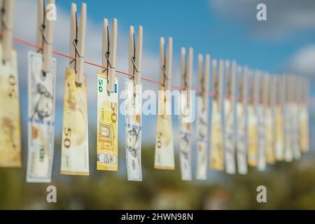 Geldwäsche-Konzept: 50 Euro und 100 Dollar Scheine, die an einer Wäscheleine mit Wäscheklammern befestigt sind. Selektiver Fokus. Stockfoto