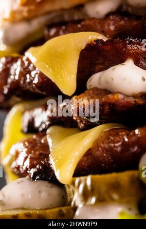 Nahaufnahme Vierfachburger mit geschmolzenem Käse und Gurke. Stockfoto