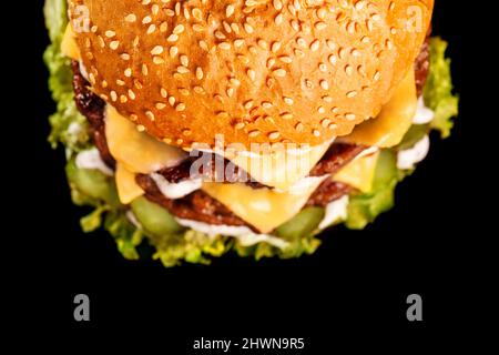 Nahaufnahme von doppeltem Käseburger mit Gurke und Salat. Blick von oben. Stockfoto