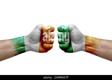 Zwei Hände schlagen sich gegenseitig auf weißem Hintergrund zu. Länderflaggen bemalten Fäuste, Konfliktkrisenkonzept zwischen irland und irland Stockfoto