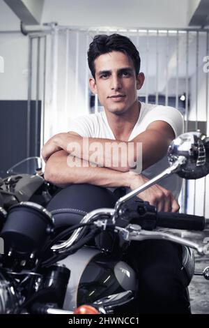 Lust auf eine Fahrt mit dem Auto? Ein hübscher junger Mann, der auf seinem Motorrad sitzt. Stockfoto