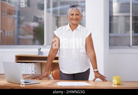 Er ist die treibende Kraft hinter dem Unternehmenserfolg. Porträt einer reifen Geschäftsfrau, die hinter ihrem Schreibtisch steht. Stockfoto