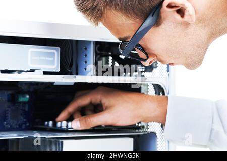 Anschließen der Drähte. Ein Hipster-Techniker, der an einem elektronischen Gerät arbeitet. Stockfoto