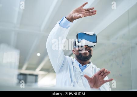 Durch die Wissenschaft eine ganz neue Welt gestalten. Aufnahme eines reifen Wissenschaftlers, der ein Virtual-Reality-Headset verwendet, während er in einem Labor arbeitet. Stockfoto