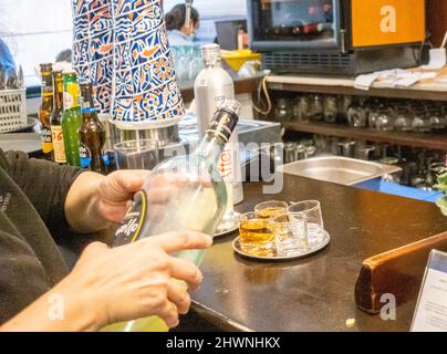 Kellnerin gießt Schnaps in der andalusischen Jugendstilbar Europa, Alfalfa, Sevilla, Spanien Stockfoto