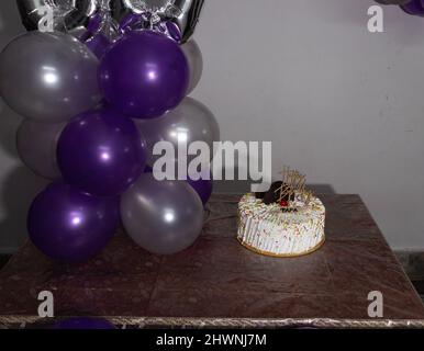 60. Geburtstagsdekorationen mit bunten Luftballons und weißen Kuchen aus verschiedenen Blickwinkeln Stockfoto