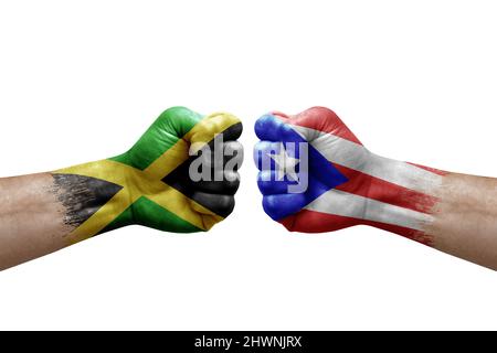 Zwei Hände schlagen sich gegenseitig auf weißem Hintergrund zu. Länderflaggen bemalten Fäuste, Konfliktkrisenkonzept zwischen jamaika und puerto rico Stockfoto
