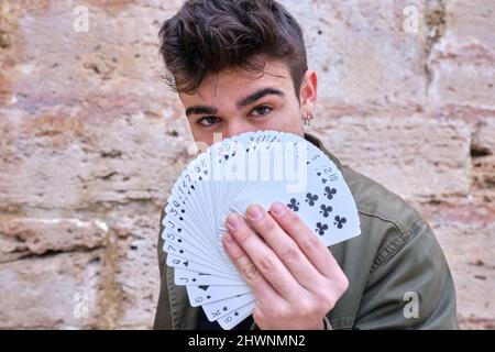 Straßenmagier versteckt sich hinter einem Kartenspiel in seiner Hand Stockfoto