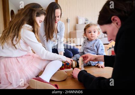 Berlin, Deutschland. 03. März 2022. Doula Denise Wilk (r) und Nina Landes spielen mit den Kindern der Familie Landes: Vicky, 8 Jahre alt und Maximilian, 1 Jahre alt. Vater und ältester Sohn können bei der Schießerei nicht anwesend sein. Neben Hebammen werden auch Doulas zunehmend für Geburten benötigt. Wilk begleitete alle drei Geburten der Mutter. Quelle: Annette Riedl/dpa/Alamy Live News Stockfoto