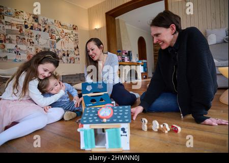 Berlin, Deutschland. 03. März 2022. Doula Denise Wilk (r) und Nina Landes spielen mit den Kindern der Familie Landes: Vicky, 8 Jahre alt und Maximilian, 1 Jahre alt. Vater und ältester Sohn können bei der Schießerei nicht anwesend sein. Neben Hebammen werden auch Doulas zunehmend für Geburten benötigt. Wilk begleitete alle drei Geburten der Mutter. Quelle: Annette Riedl/dpa/Alamy Live News Stockfoto