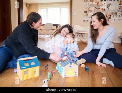 Berlin, Deutschland. 03. März 2022. Doula Denise Wilk (l) und Nina Landes spielen mit den Kindern der Familie Landes. Vicky, 8 Jahre alt und Maximilian, 1 Jahre alt. Vater und ältester Sohn können bei der Schießerei nicht anwesend sein. Neben Hebammen werden auch bei Geburten vermehrt Doulas benötigt. Wilk begleitete alle drei Geburten der Mutter. Quelle: Annette Riedl/dpa/Alamy Live News Stockfoto