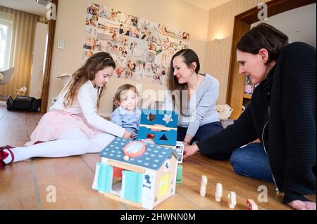 Berlin, Deutschland. 03. März 2022. Doula Denise Wilk (r) und Nina Landes spielen mit den Kindern der Familie Landes: Vicky, 8 Jahre alt und Maximilian, 1 Jahre alt. Vater und ältester Sohn können bei der Schießerei nicht anwesend sein. Neben Hebammen werden auch Doulas zunehmend für Geburten benötigt. Wilk begleitete alle drei Geburten der Mutter. Quelle: Annette Riedl/dpa/Alamy Live News Stockfoto