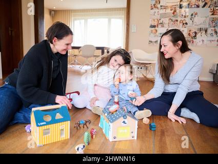 Berlin, Deutschland. 03. März 2022. Doula Denise Wilk (l und Nina Landes spielen mit den Kindern der Familie Landes: Vicky, 8 Jahre alt und Maximilian, 1 Jahre alt. Vater und ältester Sohn können bei der Schießerei nicht anwesend sein. Neben Hebammen werden auch bei Geburten vermehrt Doulas benötigt. Wilk begleitete alle drei Geburten der Mutter. Quelle: Annette Riedl/dpa/Alamy Live News Stockfoto