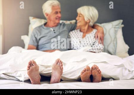 Das Aufwachen neben Ihnen ist unbezahlbar. Aufnahme eines älteren Paares, das im Bett lag. Stockfoto