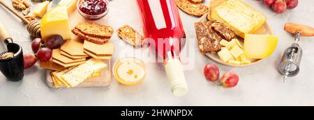 Eine Flasche Rosenwein mit Snacks auf grauem Hintergrund. Sommerdrink für Party, Weinladen oder Weinverkostungskonzept. Panorama Stockfoto