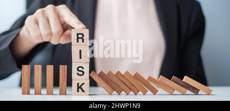 Geschäftsfrau Hand stoppen fallen Holzblöcke oder Dominosteine. Geschäfts-, Risikomanagement-, Lösungs-, Versicherungs- und Strategiekonzepte Stockfoto