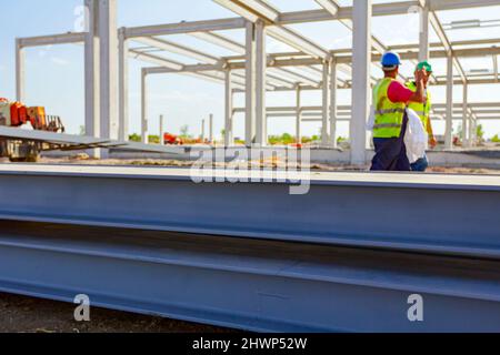 Teleskopstapler, der bis zu seinem Transport Stapel von lackierten, geschweißten Metallträgern, Struktur Träger für Metallbau auf der Baustelle. Stockfoto