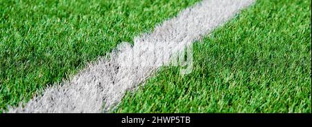 Ein Teil des Fußballfeldes aus der Nähe, künstliches grünes Gras mit weißen Randlinien, Astroturf im Stadion für Sportenspiele Stockfoto