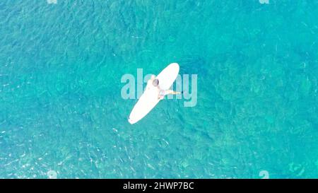 Surfer warten auf Wellen in einem klaren Wasser in der Nähe des malerischen Strandes, Blick auf die Drohne. Von oben nach unten Stockfoto