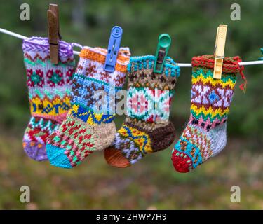 Fotografie mit gestrickten Socken, Socken, die an einem Seil hängen, Bastelkonzept, Stricken als Hobby, Kunsthandwerk sind eine gute Möglichkeit, Freizeit zu verbringen Stockfoto