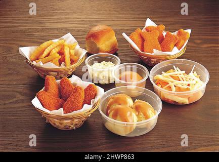 Verschiedene Snacks mit Brot, Chicken Nuggets, pommes frites, Kartoffelpüree, Krautsalat und Obstsalat Stockfoto