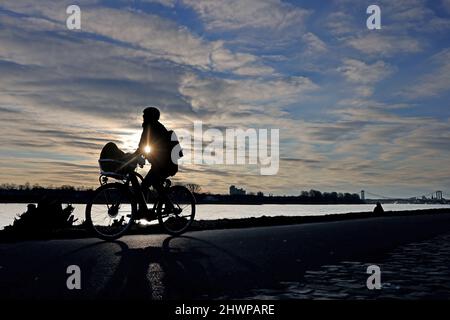 Köln, Deutschland. 07. März 2022. Ein Radfahrer fährt am Morgen des Sonnenaufgangs am Rheinufer entlang. Quelle: Oliver Berg/dpa/Alamy Live News Stockfoto