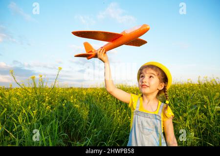 Mädchen in einem gelben panamahut startet ein Spielzeug-Flugzeug auf das Feld. Sommerzeit, glückliche Kindheit, Träume und Nachlässigkeit. Flugtour von einem Reisebüro Stockfoto