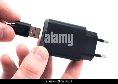 Die Hände des Mannes halten das USB-Kabel fest, um den Adapter anzuschließen. USB-Kabel auf weißem Hintergrund Stockfoto