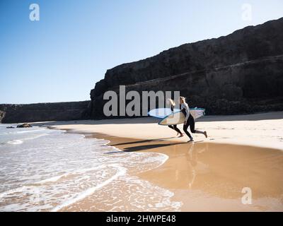 Surfer Weibchen am Strand laufen zu den Wellen Stockfoto