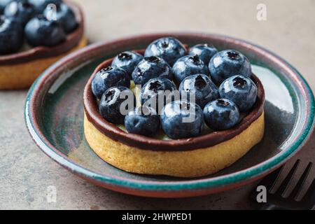 Tartlet mit Heidelbeeren, Schokolade und Frischkäse. Veganes Dessertkonzept. Stockfoto