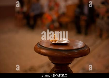 Eheringe liegen in einer goldenen Untertasse. Stand aus Holz bei der Hochzeitszeremonie. Hintergrund Hochzeit Details. Inneneinrichtung. Stockfoto