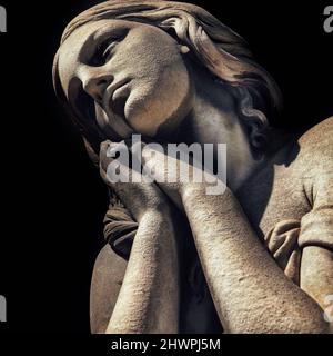 Schöne junge Mädchen Marmorstatue beten isoliert auf dunklem Hintergrund Stockfoto